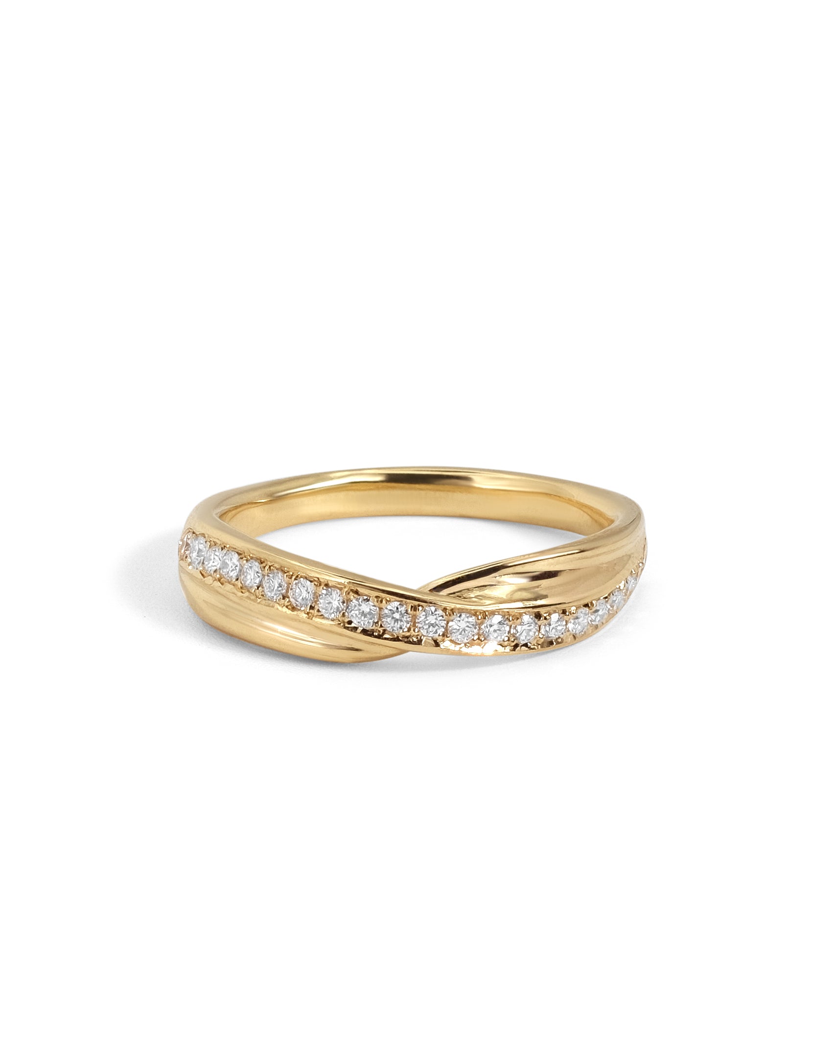 An 18 karat yellow gold wedding band with a twisted, overlapping band design, featuring a row of white pavé-set round diamonds on the front, photographed against a seamless white background.