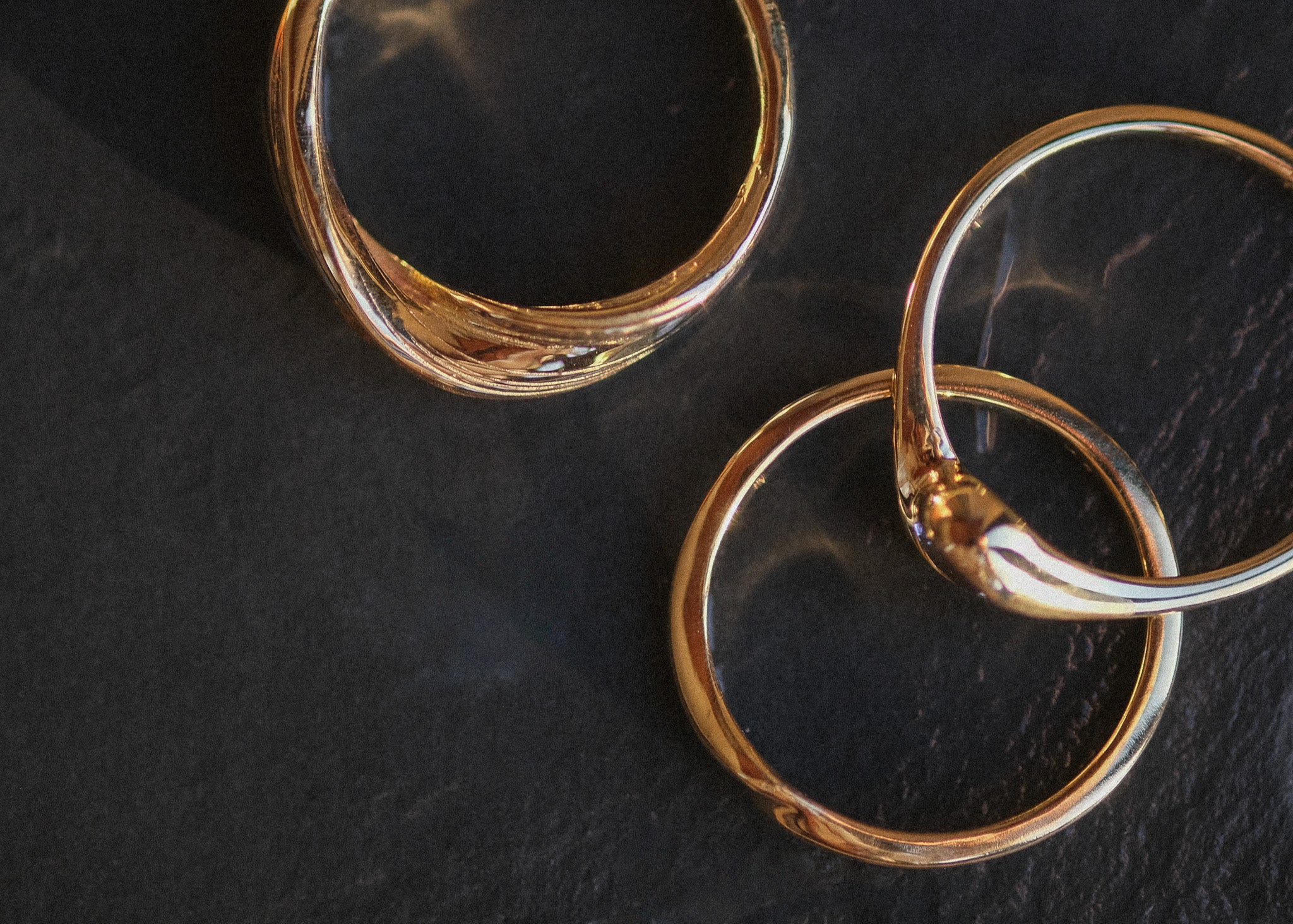 Three gold rings on a dark textured surface