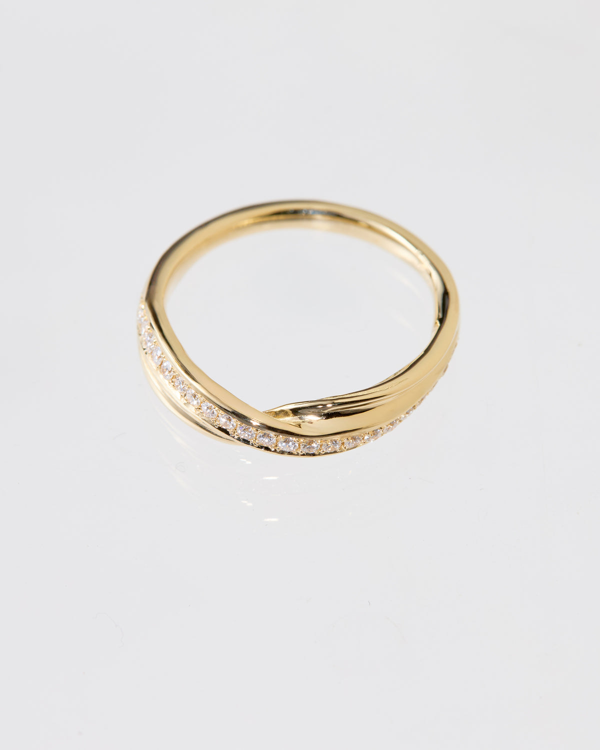A gold Mitsuro hikime ring with a twisted, wavy band design and a row of pavé diamonds along the front, photographed on a clean white background.