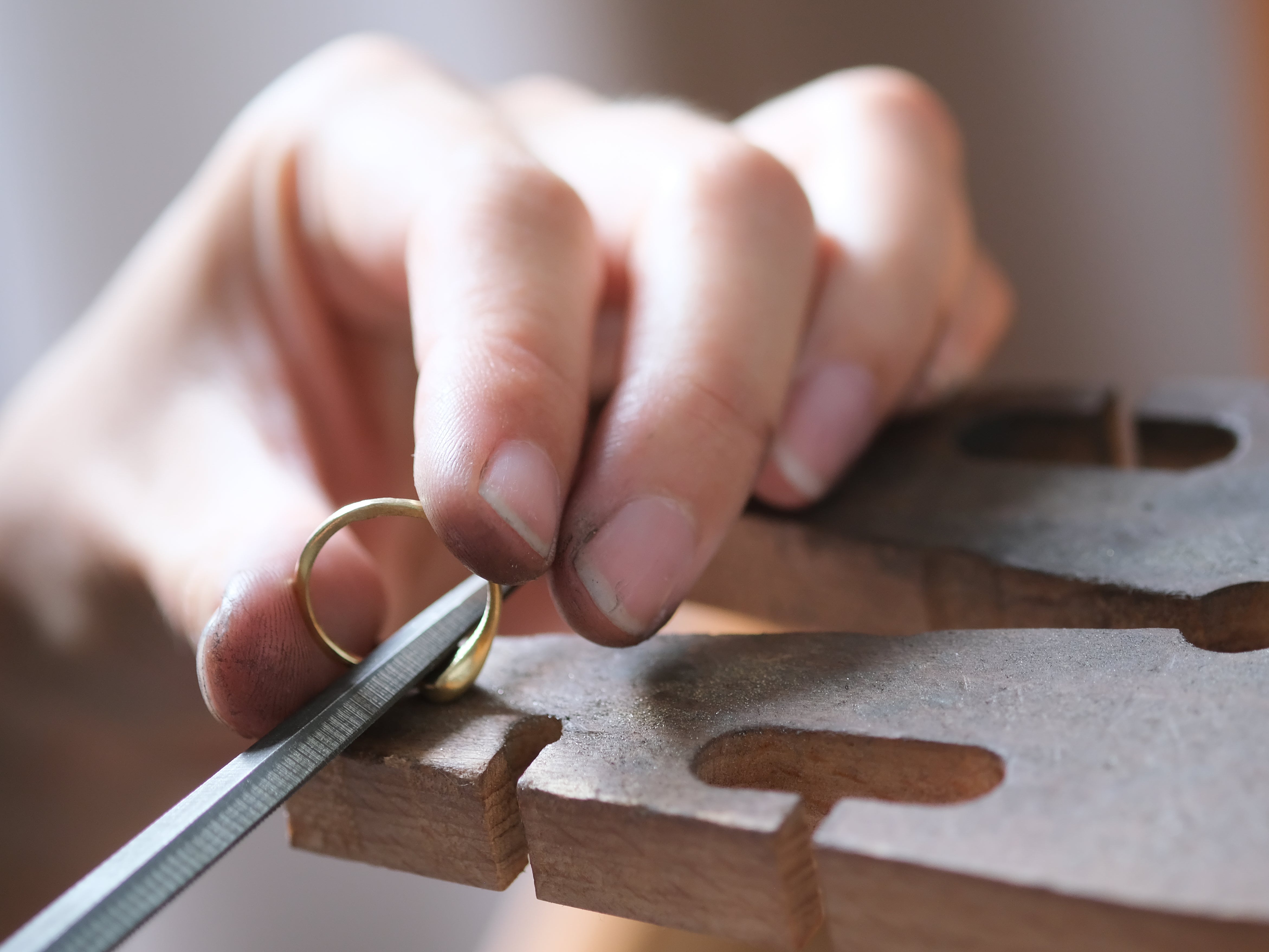 Hand with a gold ring using files on a wooden work pin