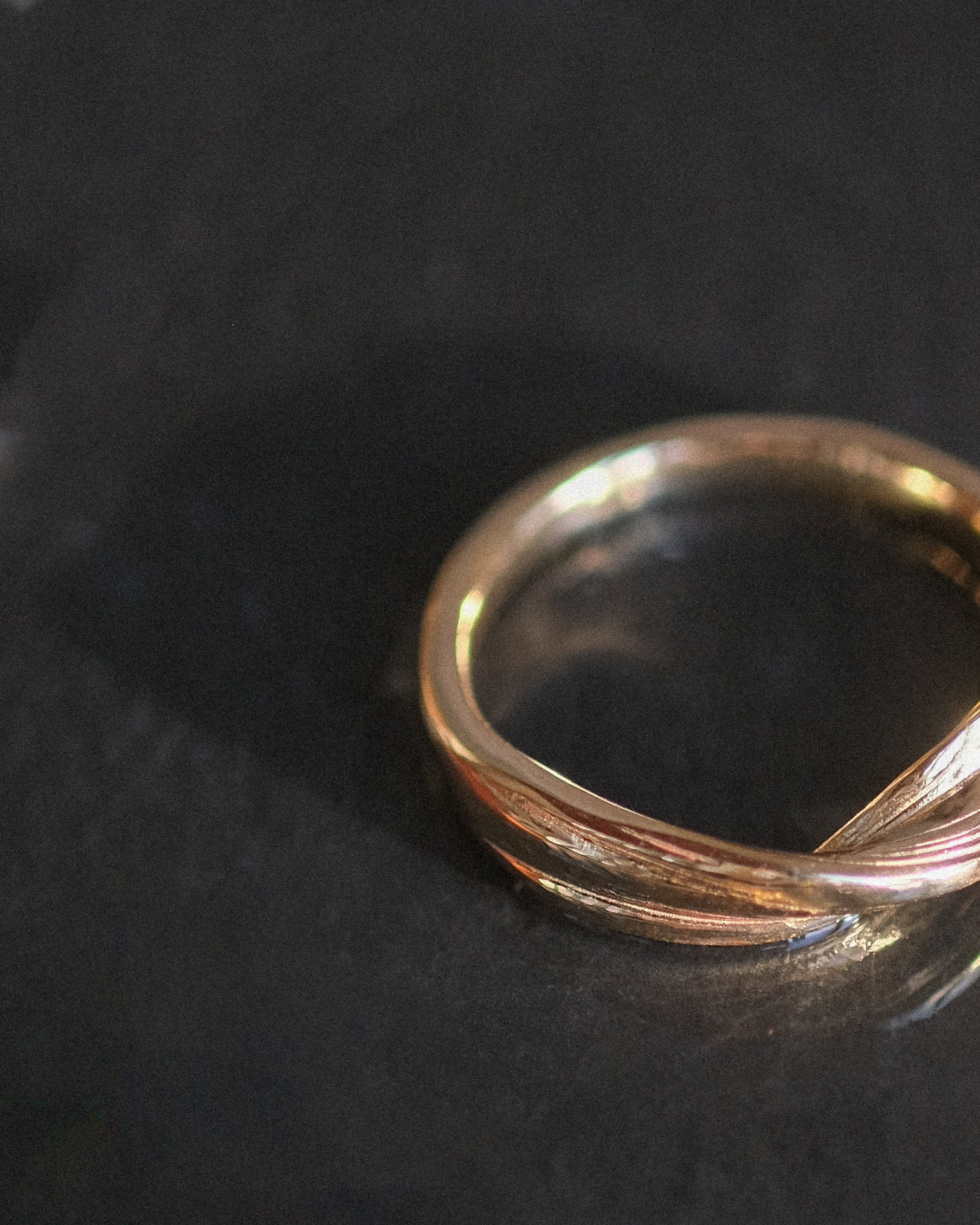 Twisting gold ring on a dark textured surface