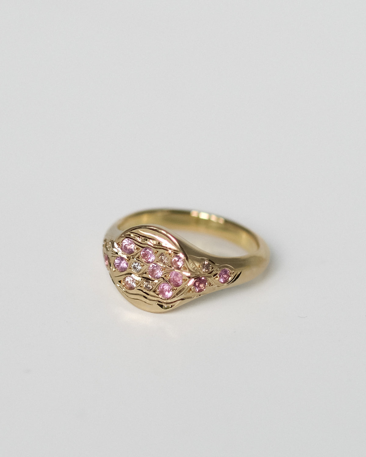 Fallen Petals Pinky Ring turning in the light, hand-set pink sapphires and champagne diamonds on engraved 18k gold.