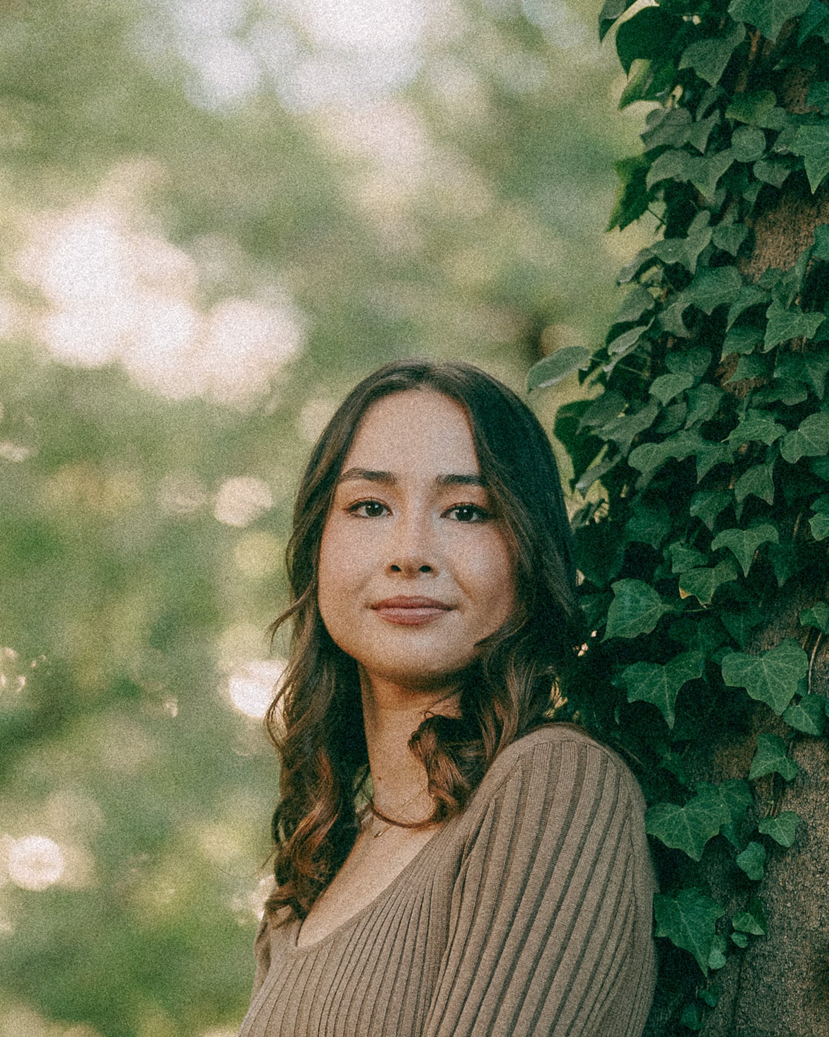Portrait photo of Anne Hara standing by a tree with ivy