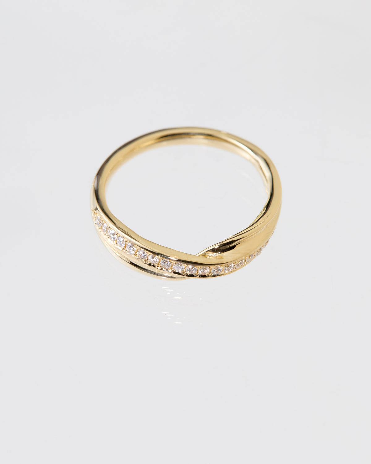 A gold Mitsuro hikime ring with a twisted, wavy band design and a row of pavé diamonds along the front, photographed on a clean white background.