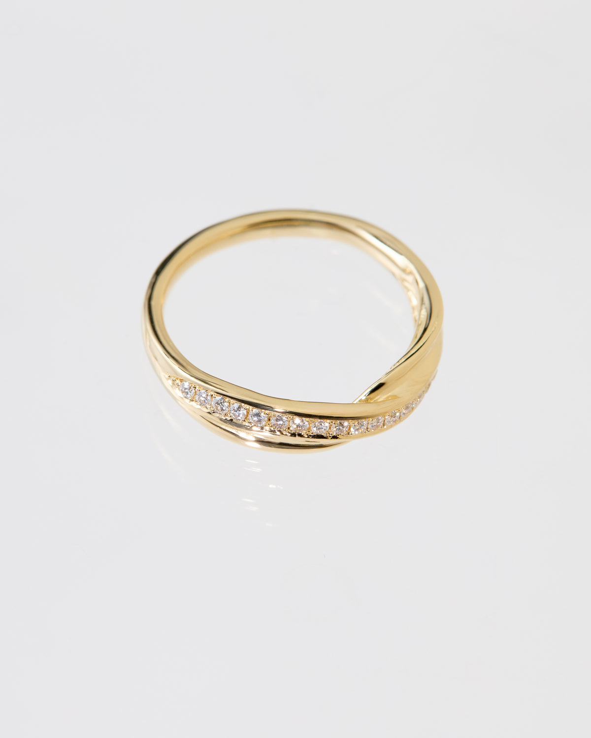 A gold Mitsuro hikime ring with a twisted, wavy band design and a row of pavé diamonds along the front, photographed on a clean white background.