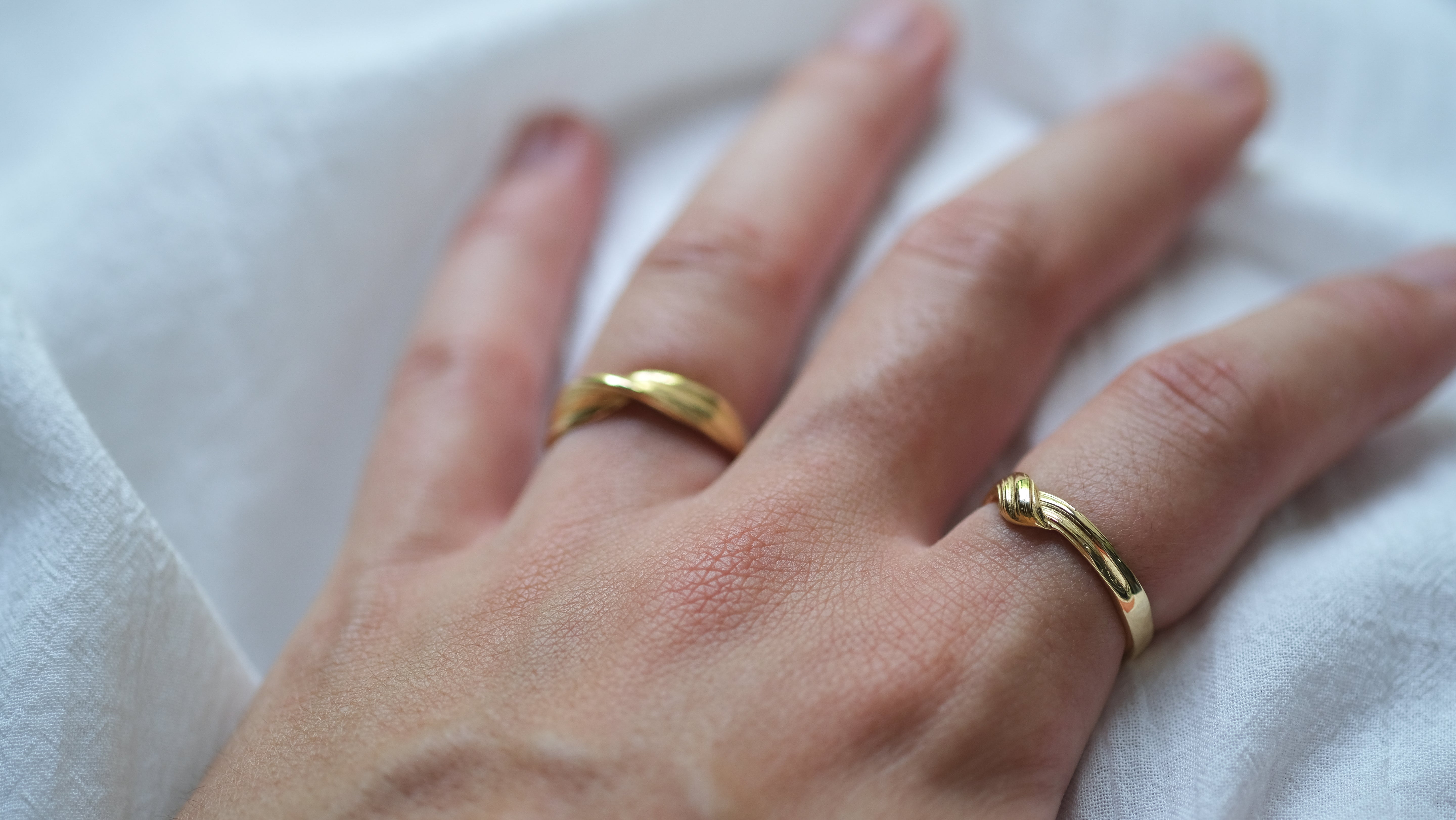 Gold rings on a person's fingers against a white background