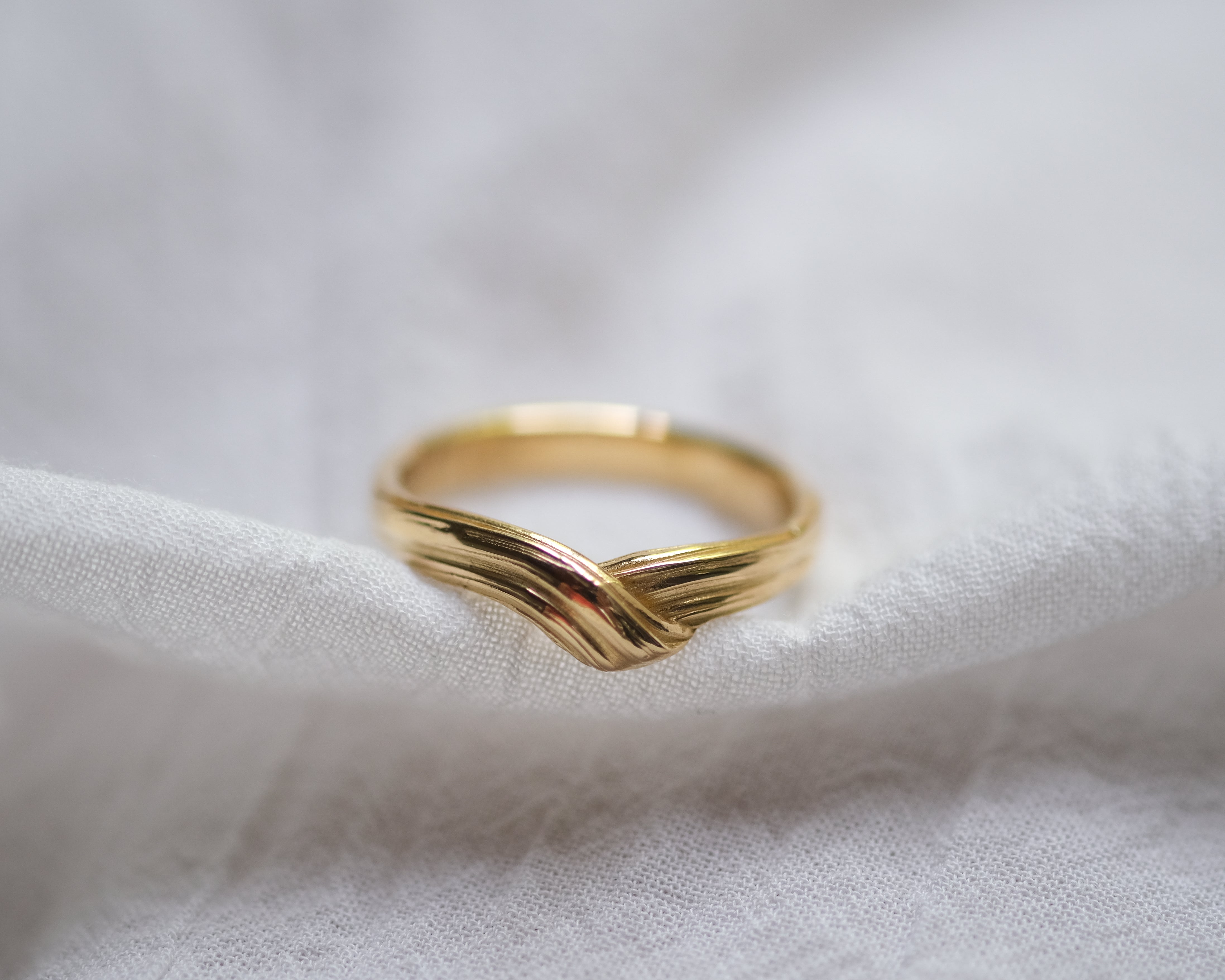 Textured gold ring on a white fabric background