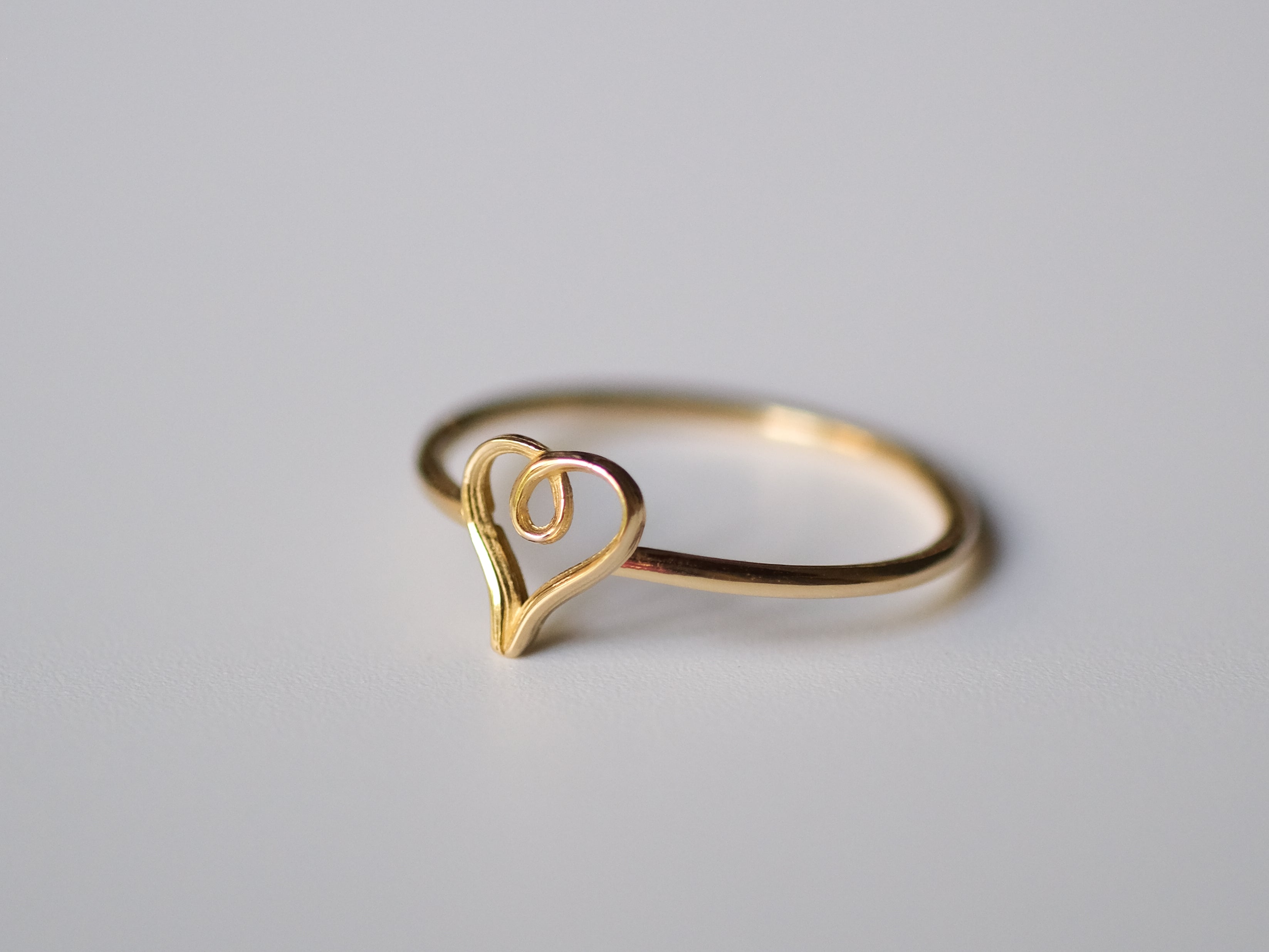Gold heart-shaped ring on a light gray background