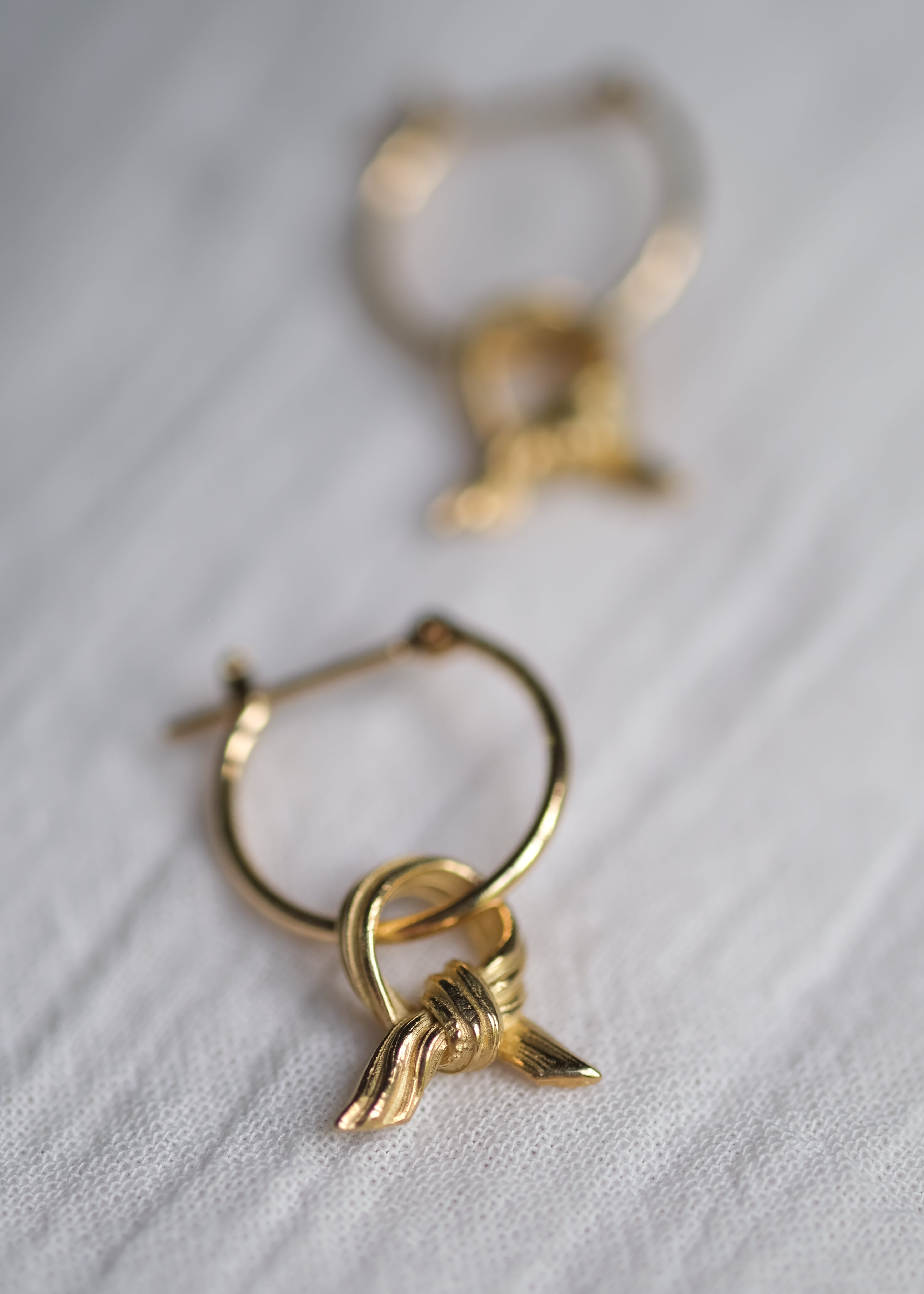 Gold hoop earrings with a unique design on a light fabric background