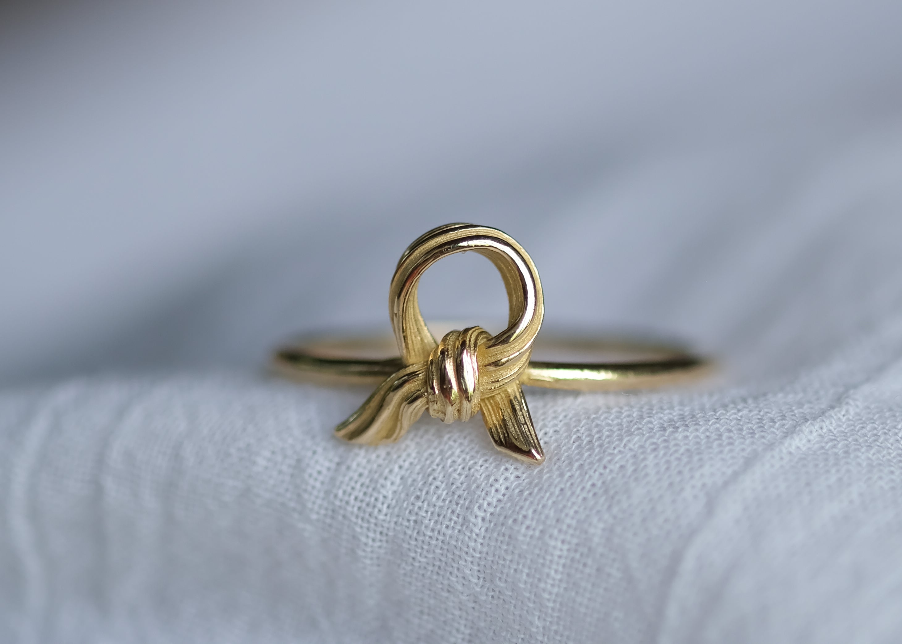 Gold ring with a unique knot design on a light fabric background